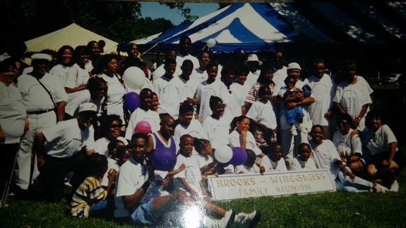 Large Brooks-Wineglass family group photo outdoors with reunion banner