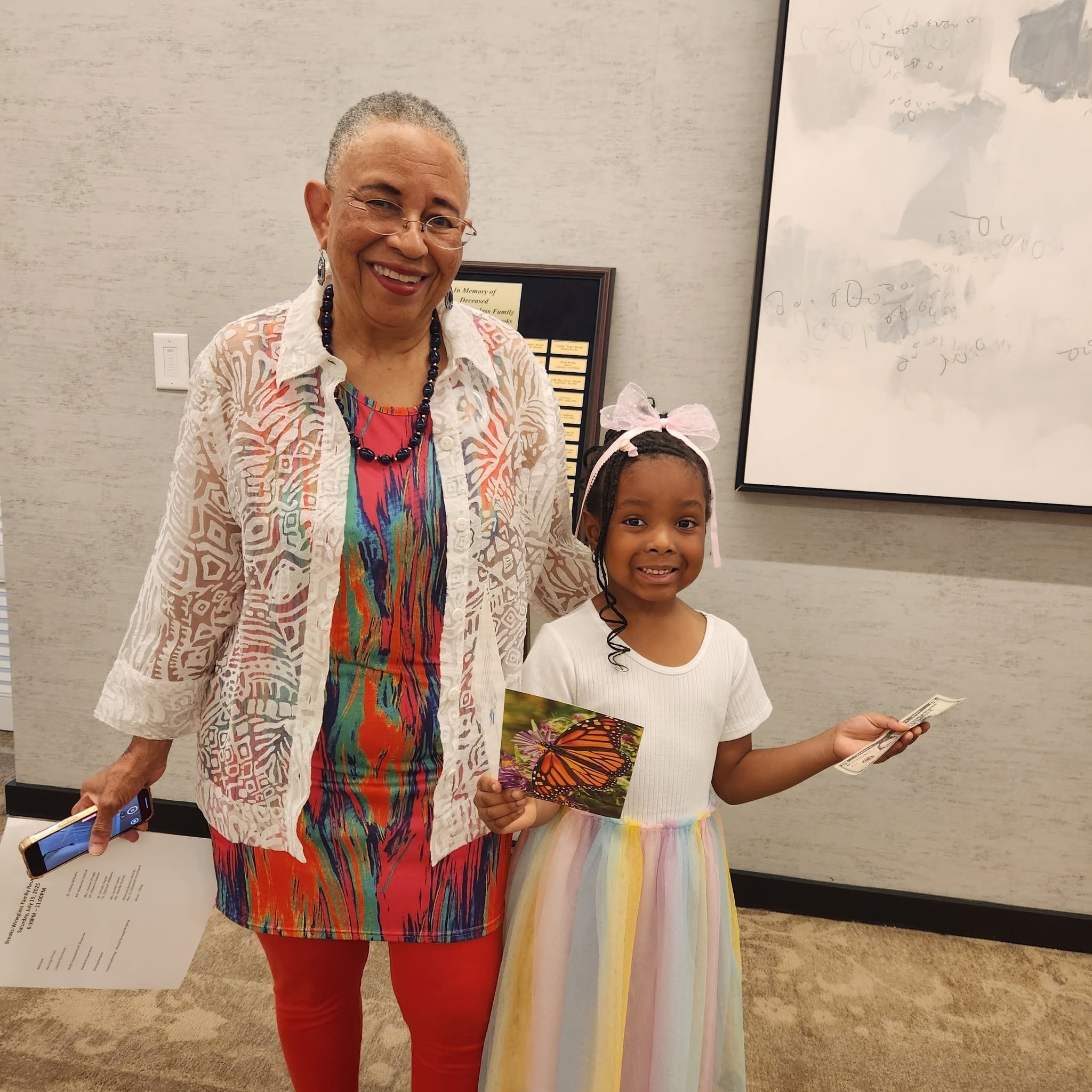 Grandmother and granddaughter holding a butterfly painting at the reunion