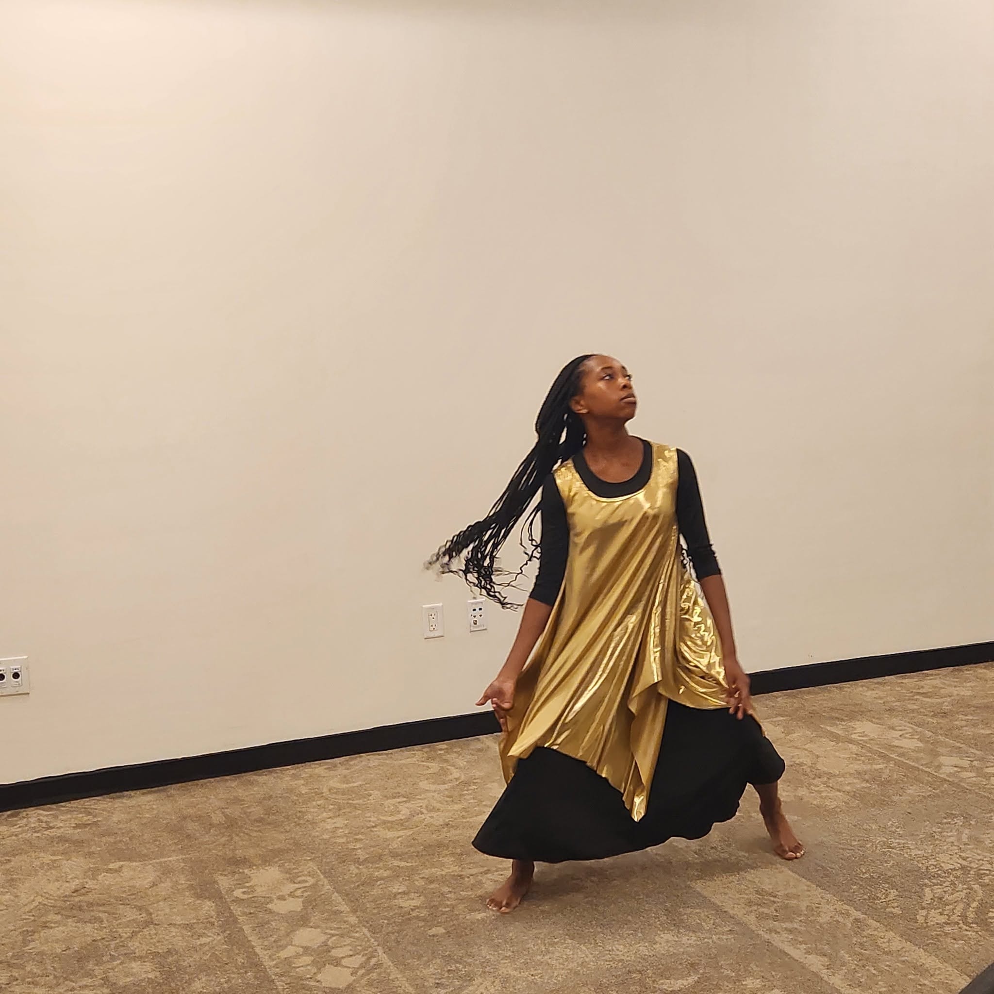 Young woman performing a praise dance in a gold dress at the reunion