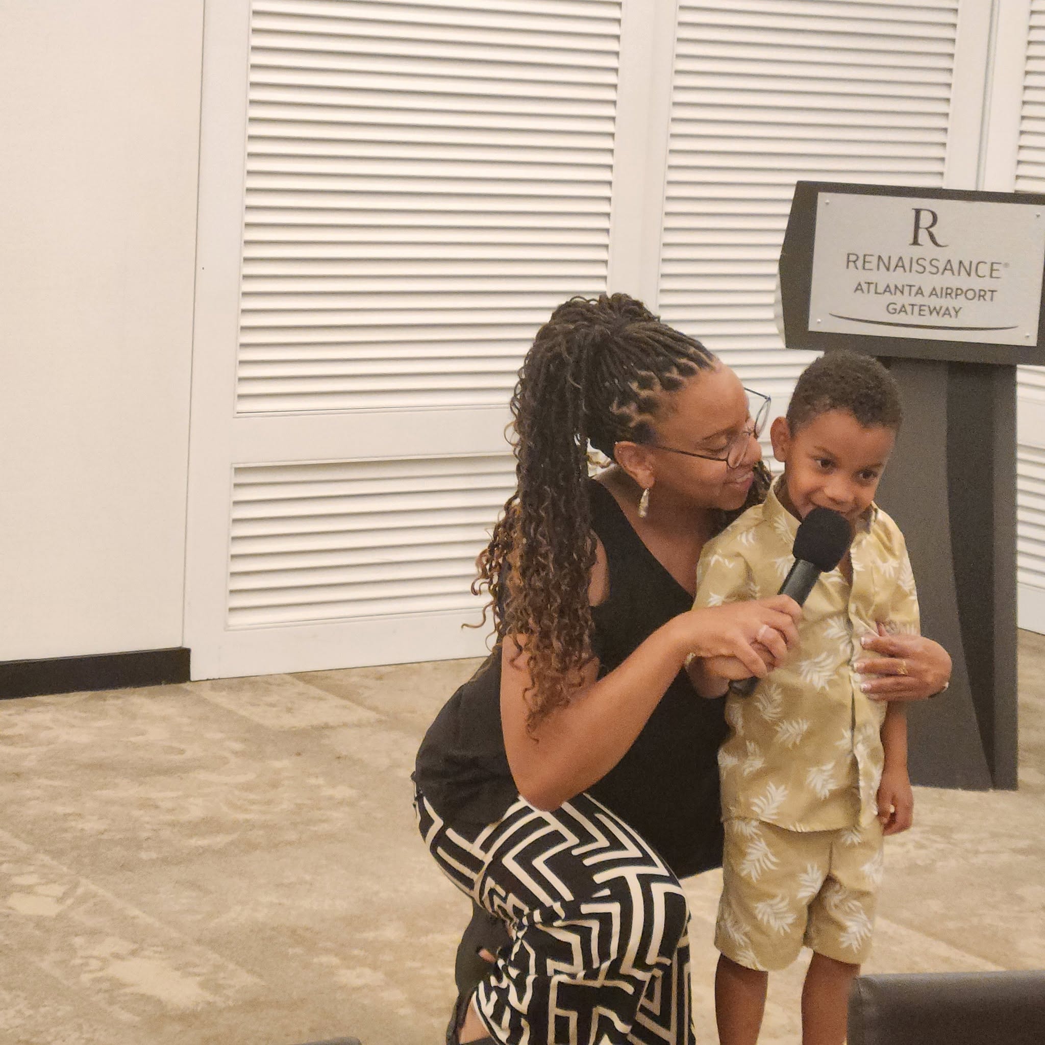 Family member holding a microphone with a young boy at the Renaissance Atlanta reunion