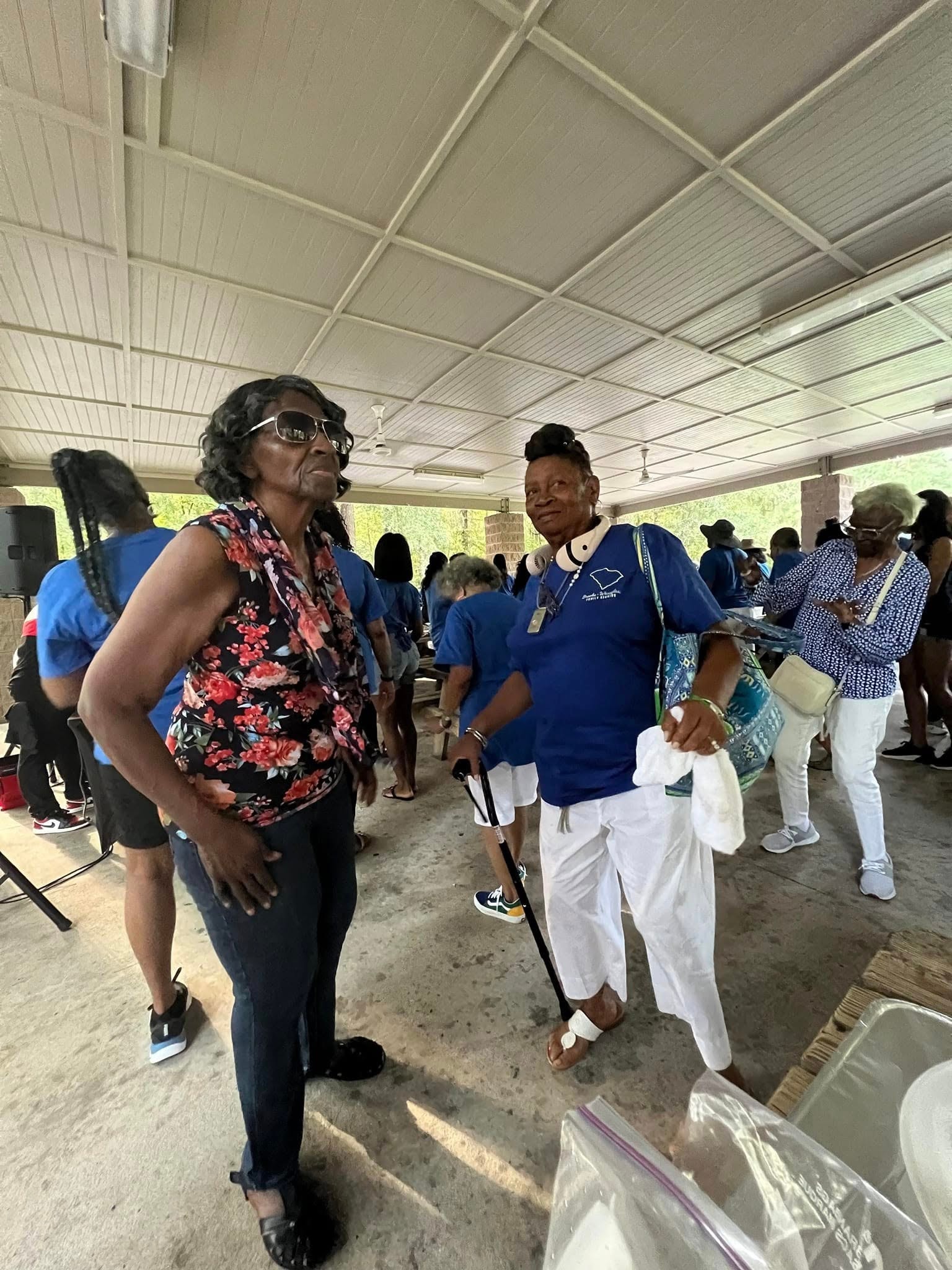 Two women chatting at the outdoor reunion picnic in blue shirts