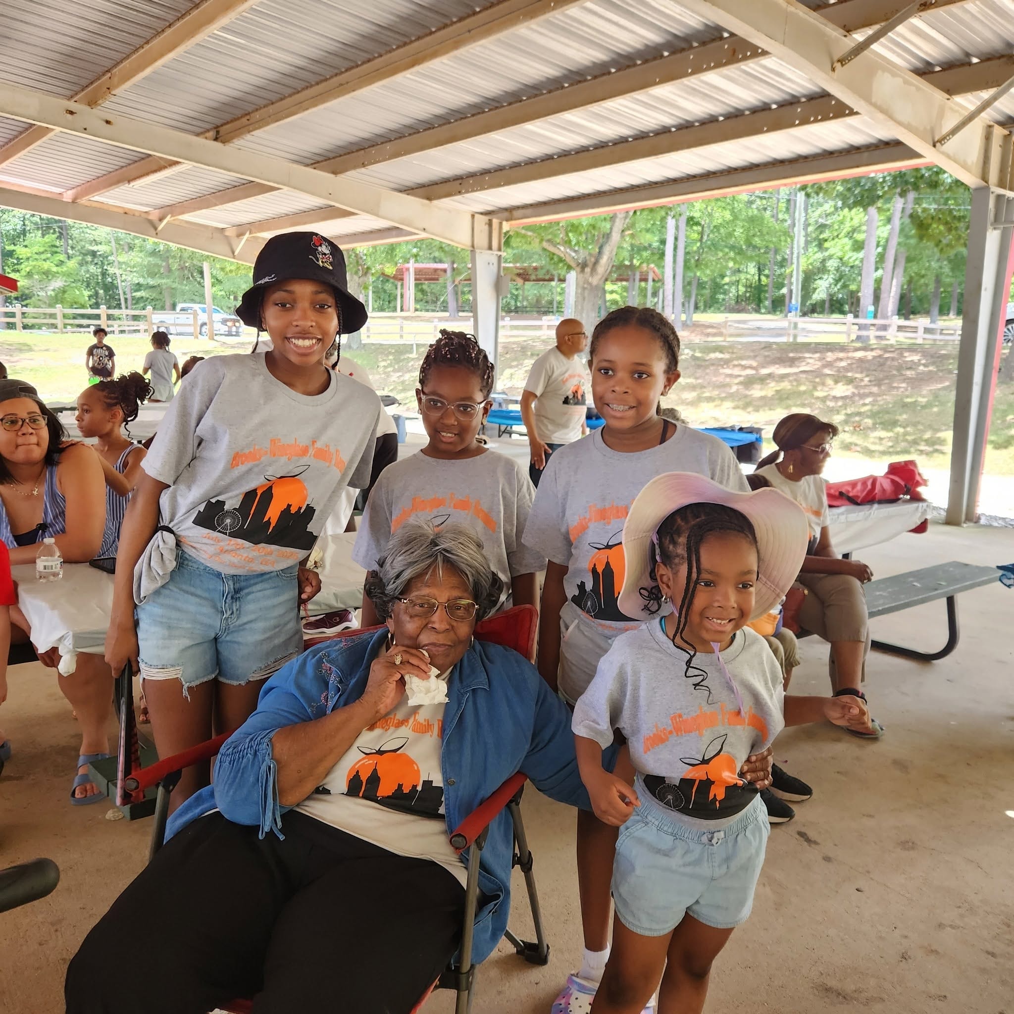 Grandmother seated with grandchildren in Brooks-Wineglass reunion shirts at the park pavilion